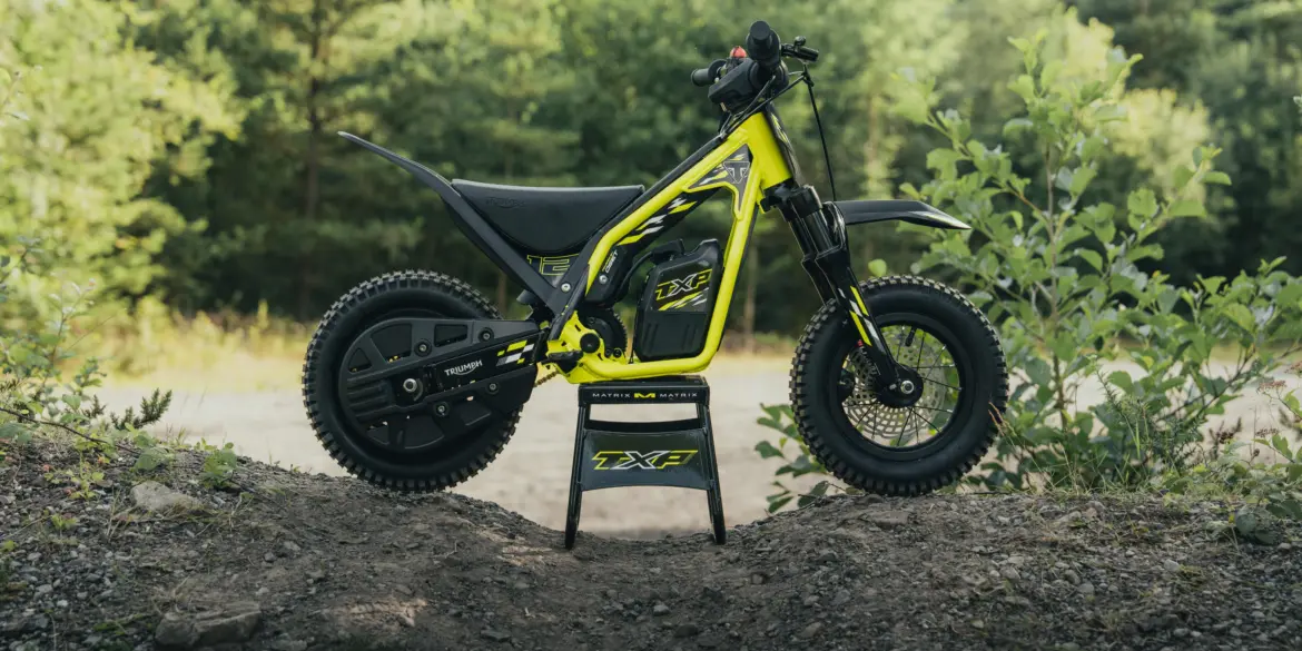 Triumph TXP-12 Elektromotorrad für Kinder im Gelände, Seitenansicht auf einem Erdwall