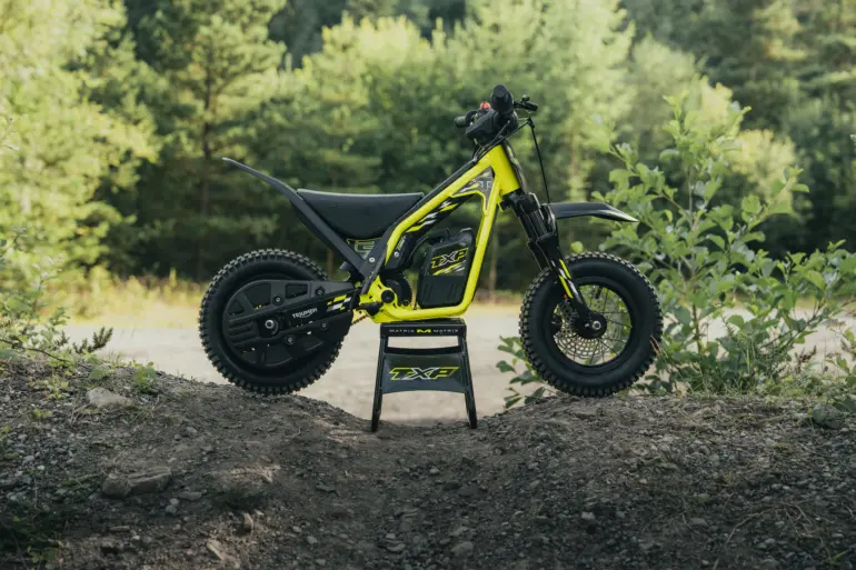 Triumph TXP-12 Elektromotorrad für Kinder im Gelände, Seitenansicht auf einem Erdwall