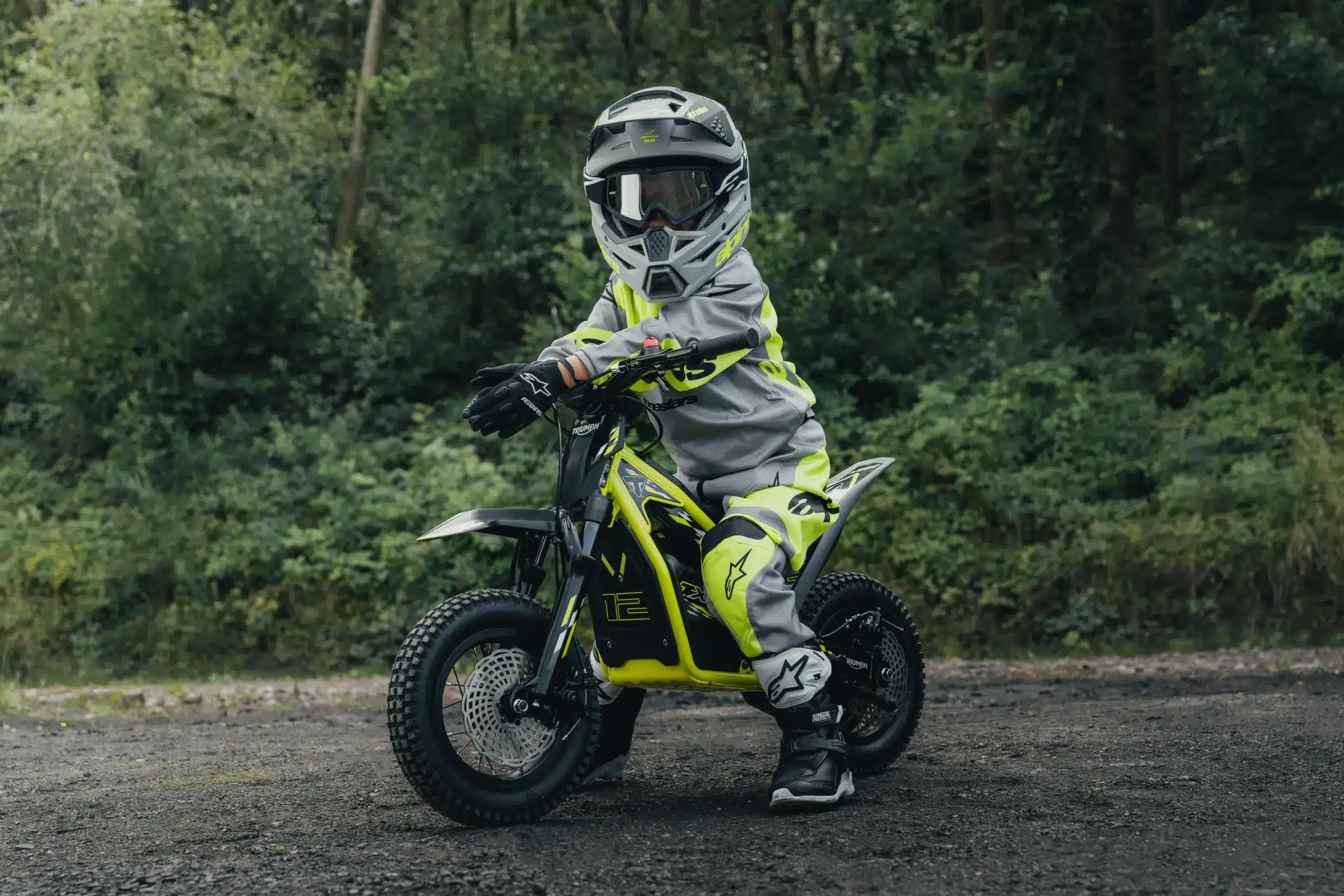 Junger Fahrer auf einer Triumph TXP-12 im Offroad-Outfit im Waldgebiet