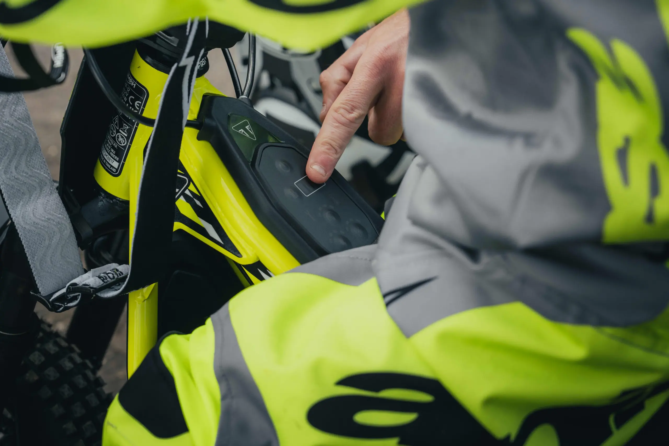 Detailansicht eines Fingers auf dem Bedienfeld der Triumph TXP-12, einem elektrischen Kinder-Motorrad.