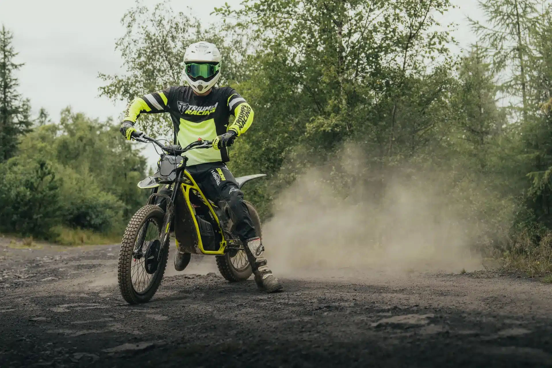 Motorradfahrer auf einer Triumph TXP-24 fährt auf einem staubigen Offroad-Weg.
