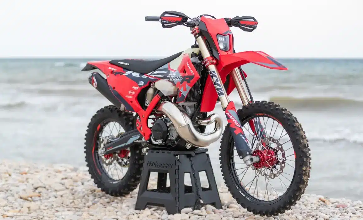 Rieju MR 300i PRO 2027 Enduro-Motorrad mit neuem Dekor auf einem Kiesstrand vor dem Meer.