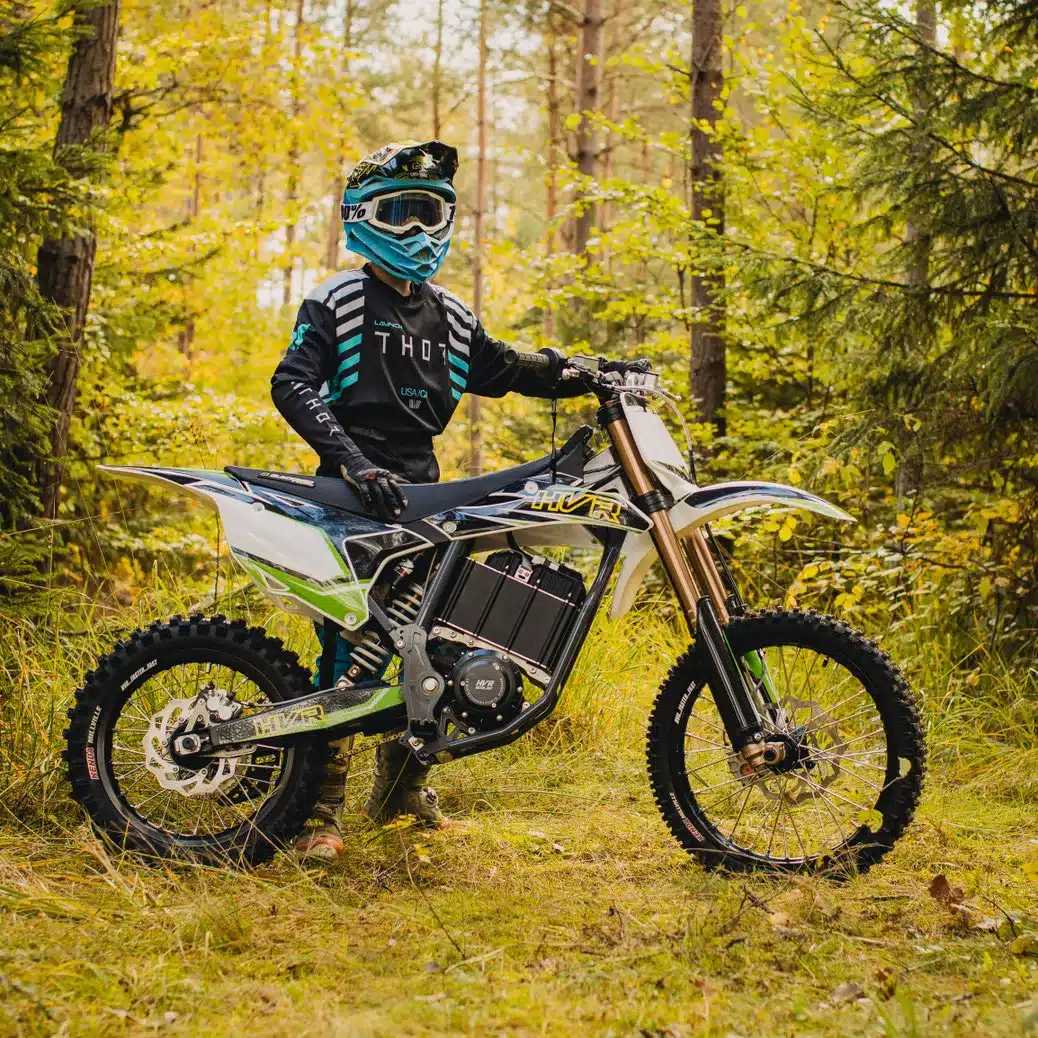 Junger Fahrer im Motocross-Outfit steht mit HVR 85PRO Elektromotorrad auf einer Waldlichtung.