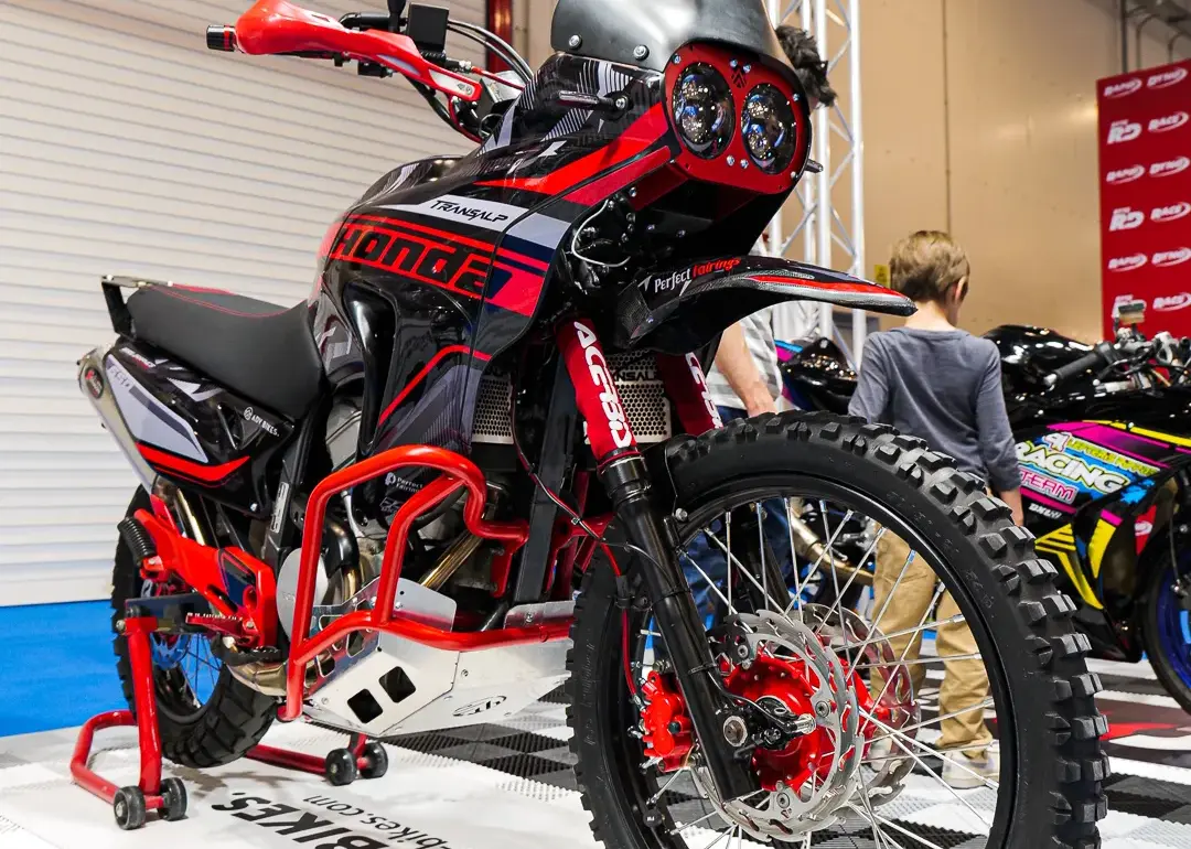 Honda XL650V Transalp als Adventure-Umbau mit Rallye-Front, Motorschutz und Navigation Tower auf einer Ausstellungsfläche.