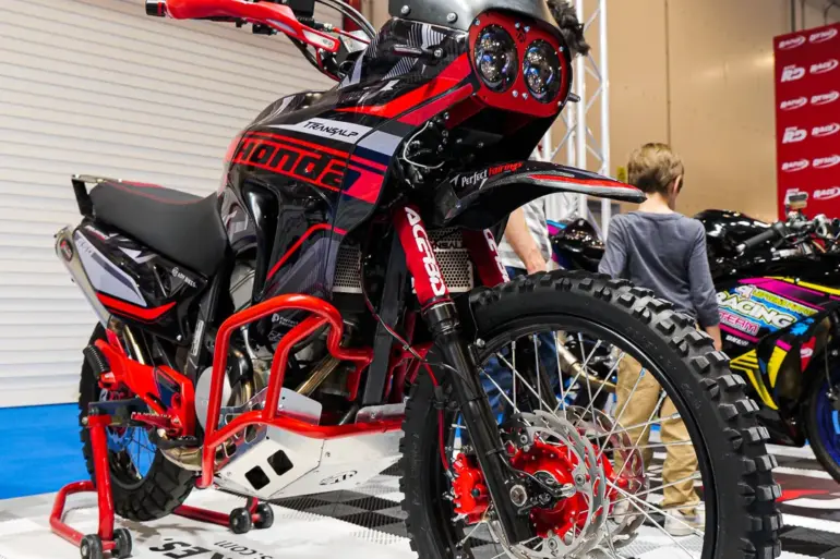 Honda XL650V Transalp als Adventure-Umbau mit Rallye-Front, Motorschutz und Navigation Tower auf einer Ausstellungsfläche.