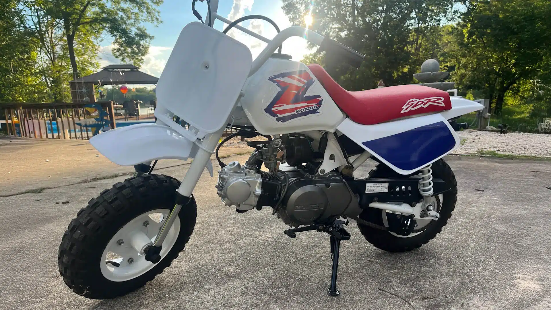 1995 Honda Z50R Mini-Motorrad mit rotem Sitzbank und klassischem Z-Logo, aufgenommen auf einem Vorplatz bei Sonnenschein.