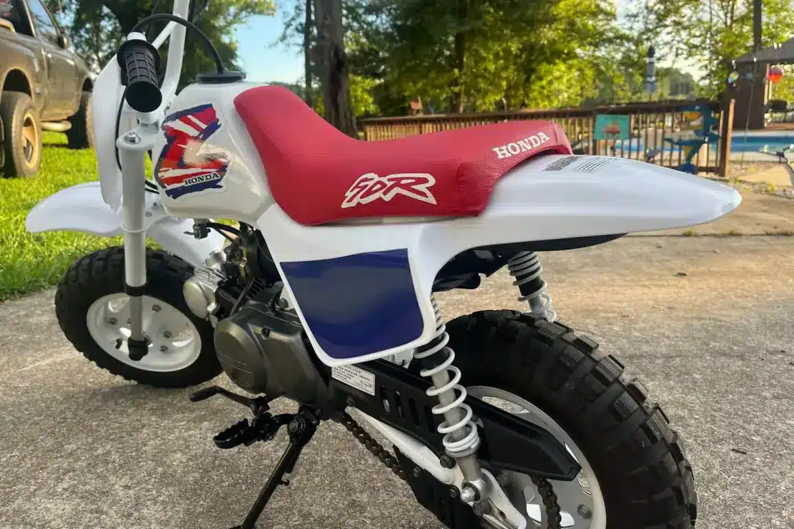 Klassische 1995 Honda Z50R mit rotem Sitz und weiß-blauer Verkleidung, im Freien abgestellt.