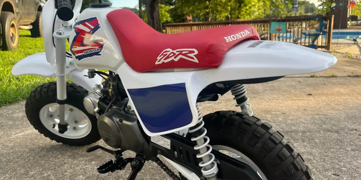 Klassische 1995 Honda Z50R mit rotem Sitz und weiß-blauer Verkleidung, im Freien abgestellt.
