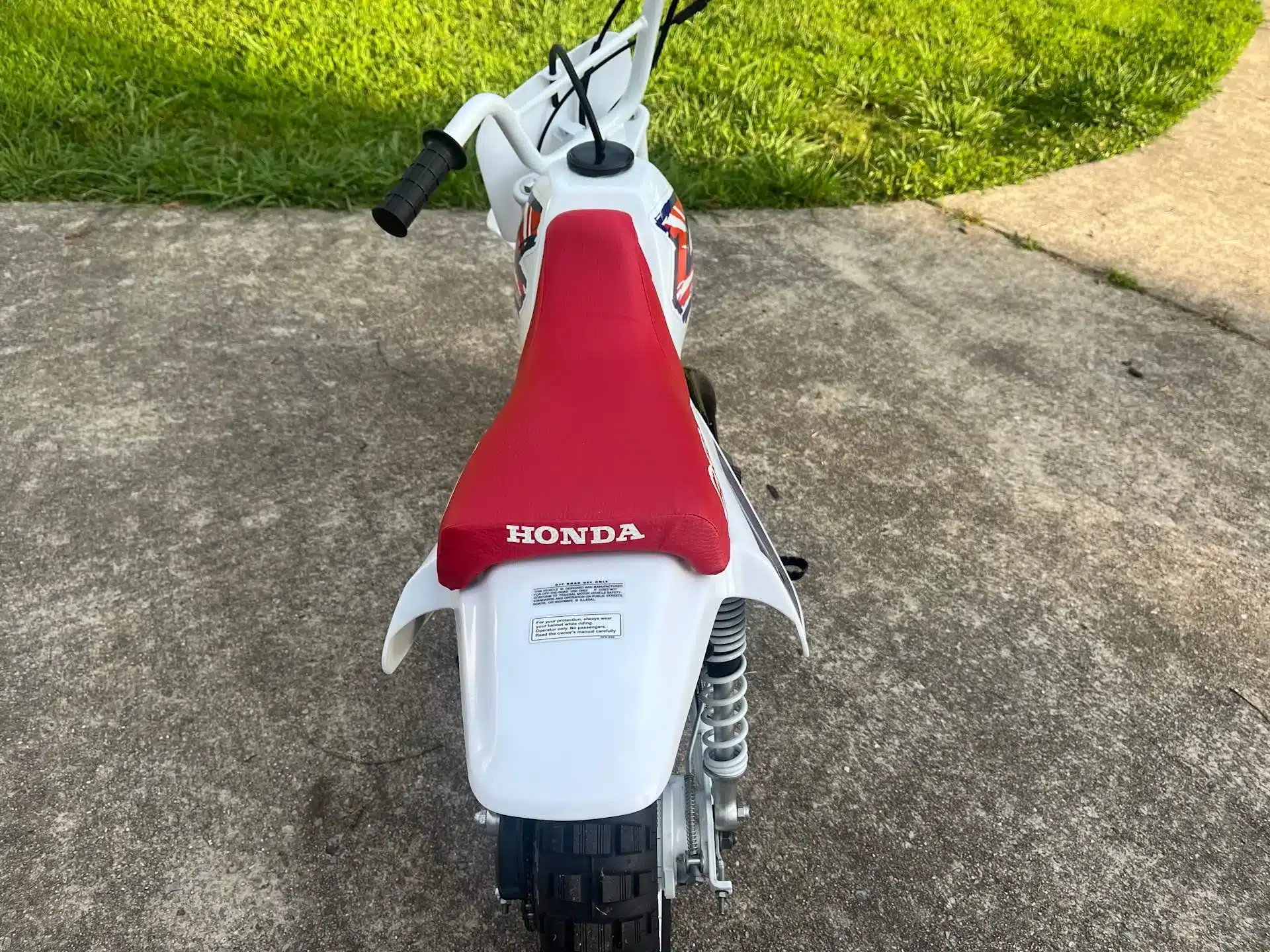Rote Sitzbank und Rückansicht einer Honda Z50R von 1995 auf Betonuntergrund