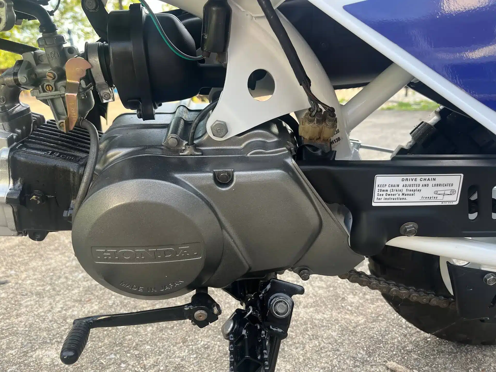 Nahaufnahme des Motors und Rahmens einer Honda Z50R, Baujahr 1995, mit sichtbarem Kettentrieb und technischem Aufkleber