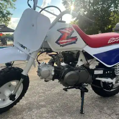 Restaurierte Honda Z50 von 1995 mit weiß-blau-rotem Farbschema, originalem Tank, rotem Sitz und korrekt angebrachtem Z-Logo, abgestellt im Außenbereich.