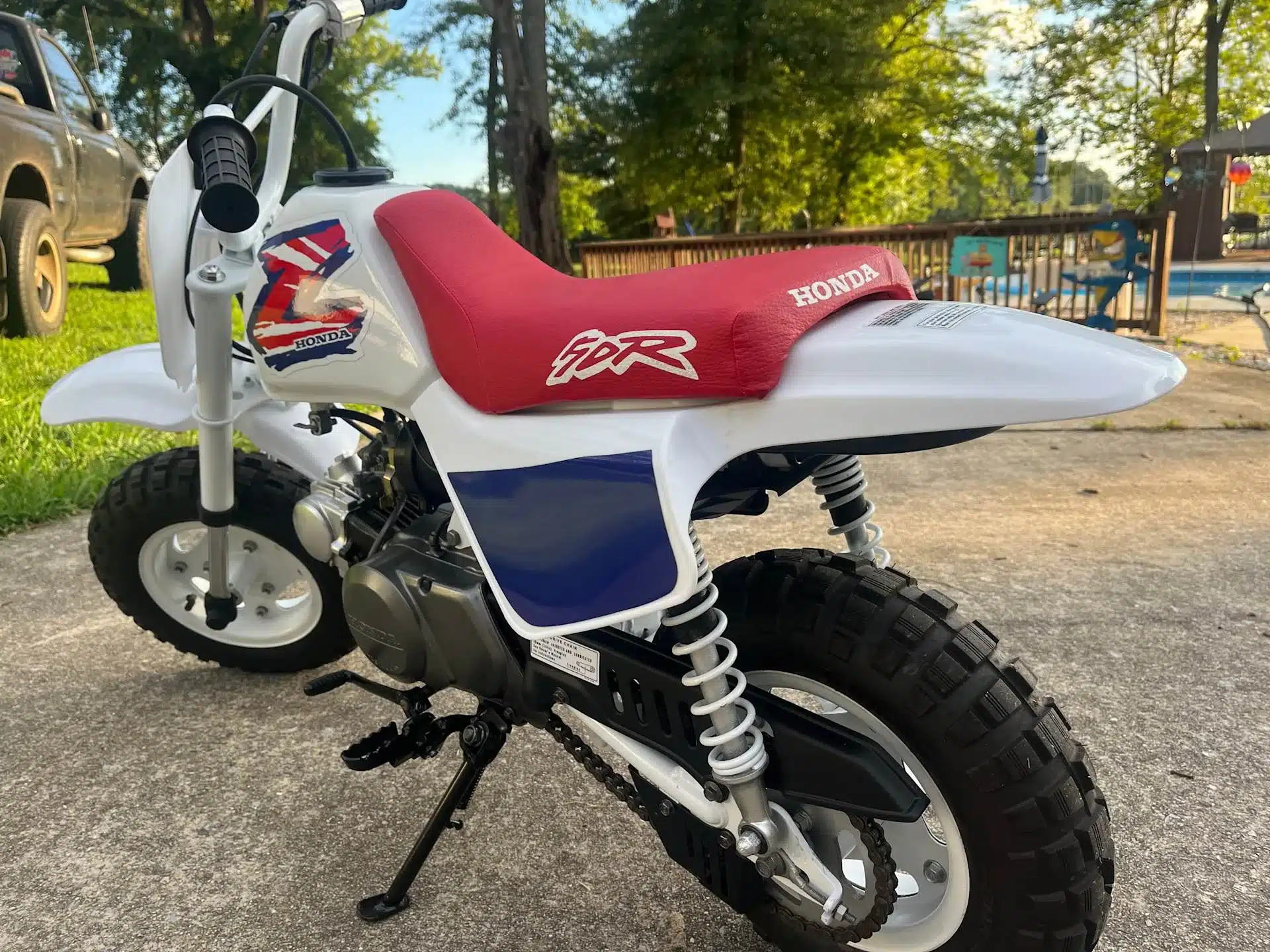 Seitenansicht einer restaurierten Honda Z50 in Shasta White und mit rotem Sitz, originalem Tank und Dekoren.