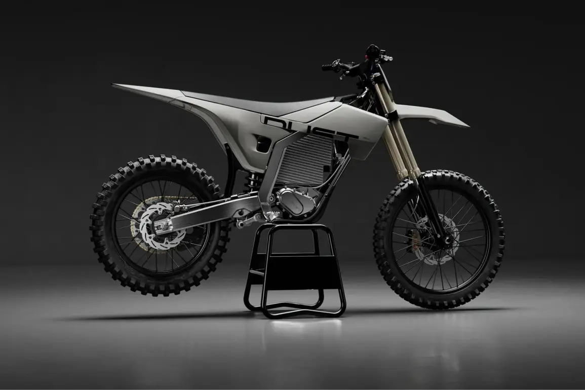 Elektrisches Dirtbike von Dust Moto auf einem Ständer vor dunklem Hintergrund.