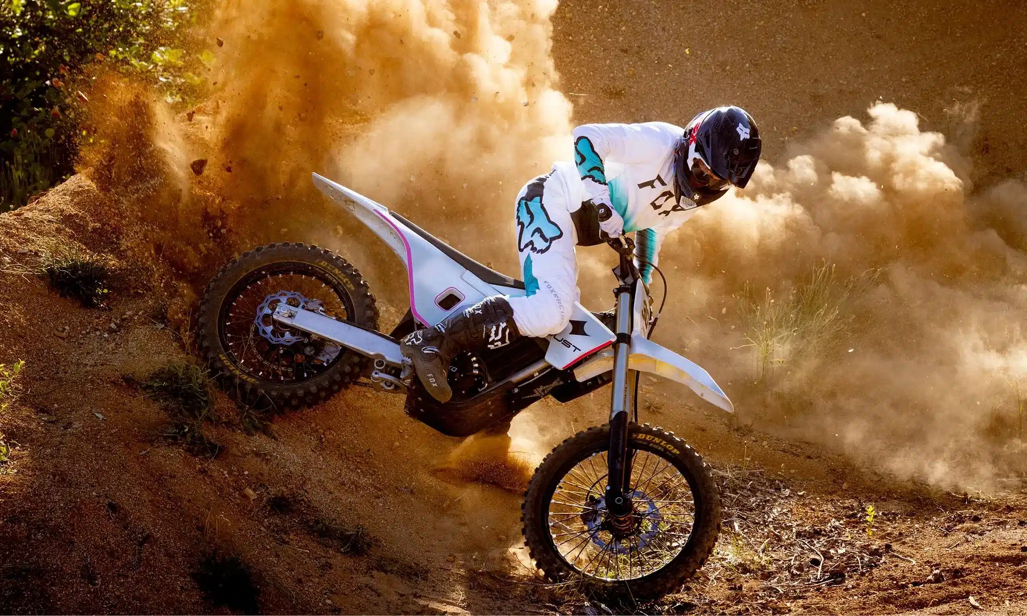 Fahrer fährt ein elektrisches Dirtbike von Dust Moto durch eine staubige Offroad-Kurve