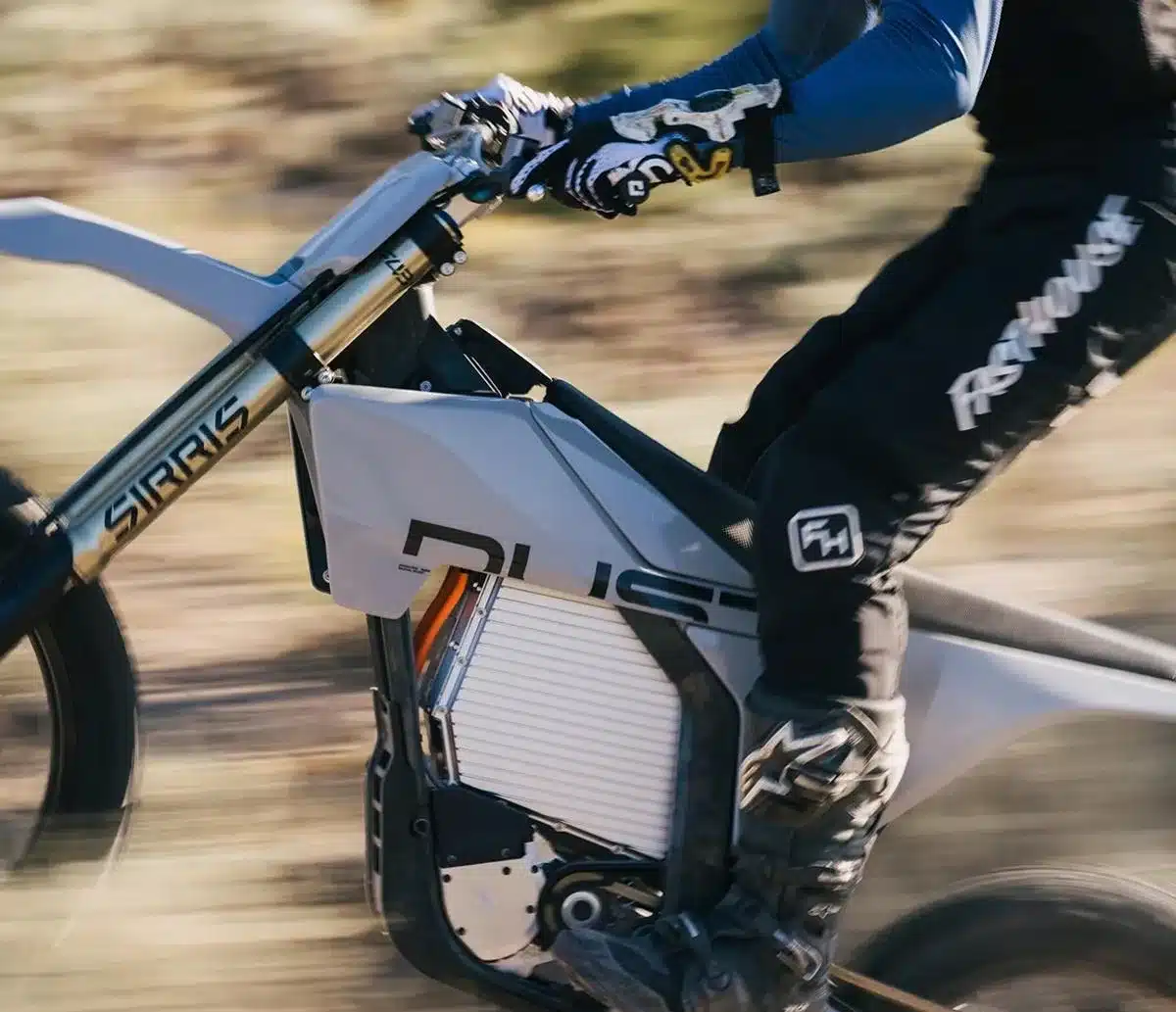 Seitenansicht eines Dust Moto Elektro-Dirtbikes mit Fahrer im Offroad-Gelände
