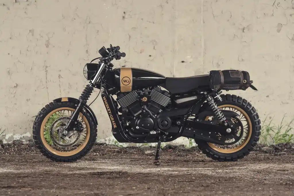 Custom Harley-Davidson Street 750 Scrambler-Umbau mit Stollenreifen und Individualteilen vor heller Wand