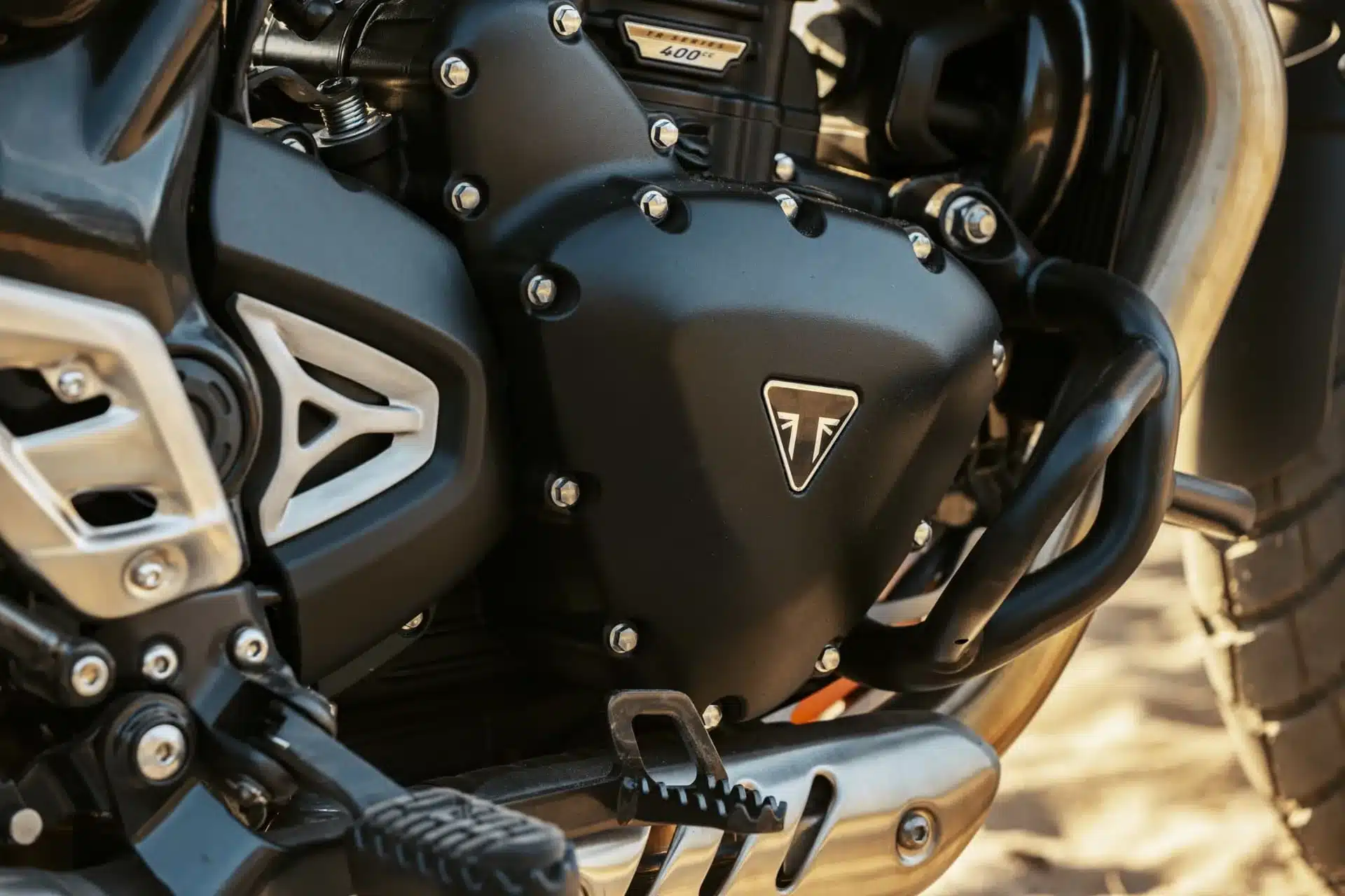 Nahaufnahme des Motors einer Triumph Scrambler 400 XC mit Motorschutzbügel und Fußraste.