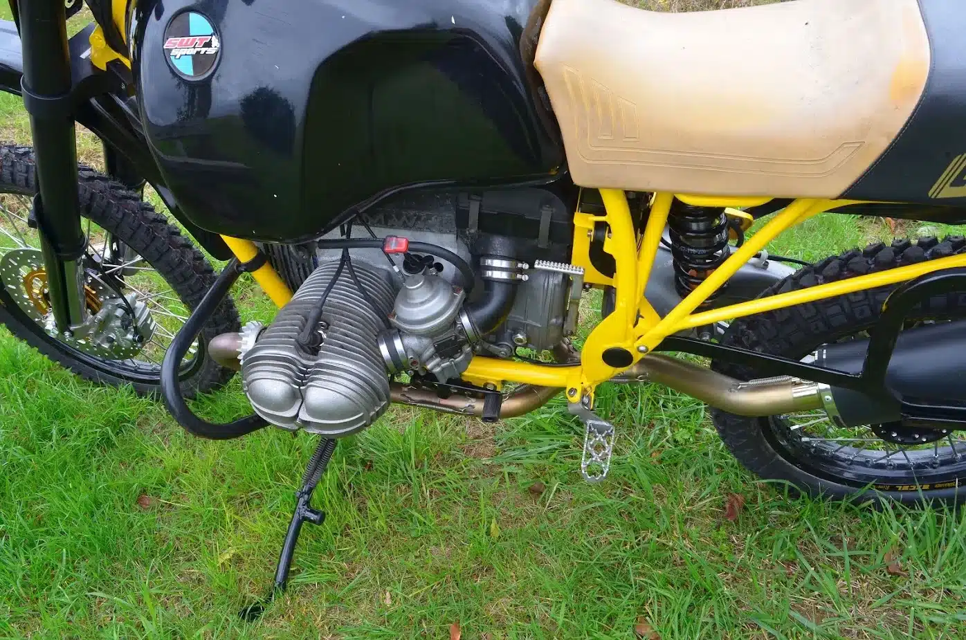 Detailansicht des BMW GS Umbau-Motorrads von SWT-SPORTS mit Boxermotor, gelbem Rahmen und modernen Fahrwerkskomponenten im Gras