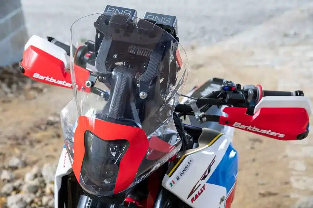 Nahaufnahme vom Cockpit einer AQ-Honda CRF 1000R EVO mit Rallye-Instrumenten und roten Barkbusters-Handprotektoren
