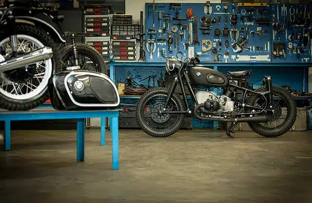 BMW R50 Motorrad aus dem Jahr 1955 nach behutsamem Neuaufbau in einer Werkstatt vor blauer Werkzeugwand
