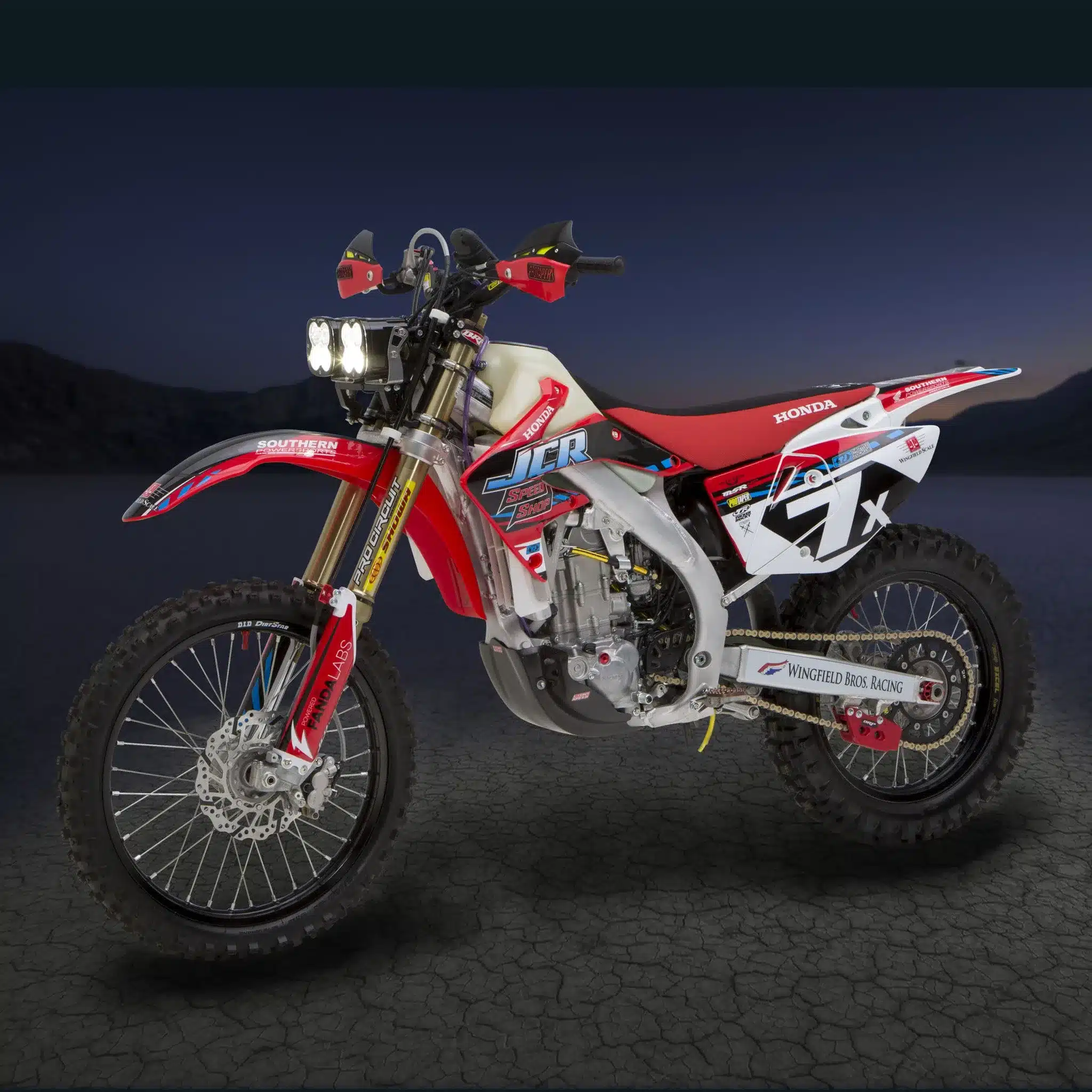 Honda CRF450X Baja 1000 Racer mit JCR-Umbauten, Baja Designs LED-Lichtanlage, und Rennaufbau seitlich fotografiert.